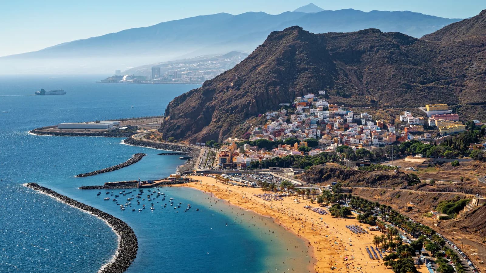 Vista aérea de una playa de arena dorada en el sur de Tenerife con el Teide al fondo
