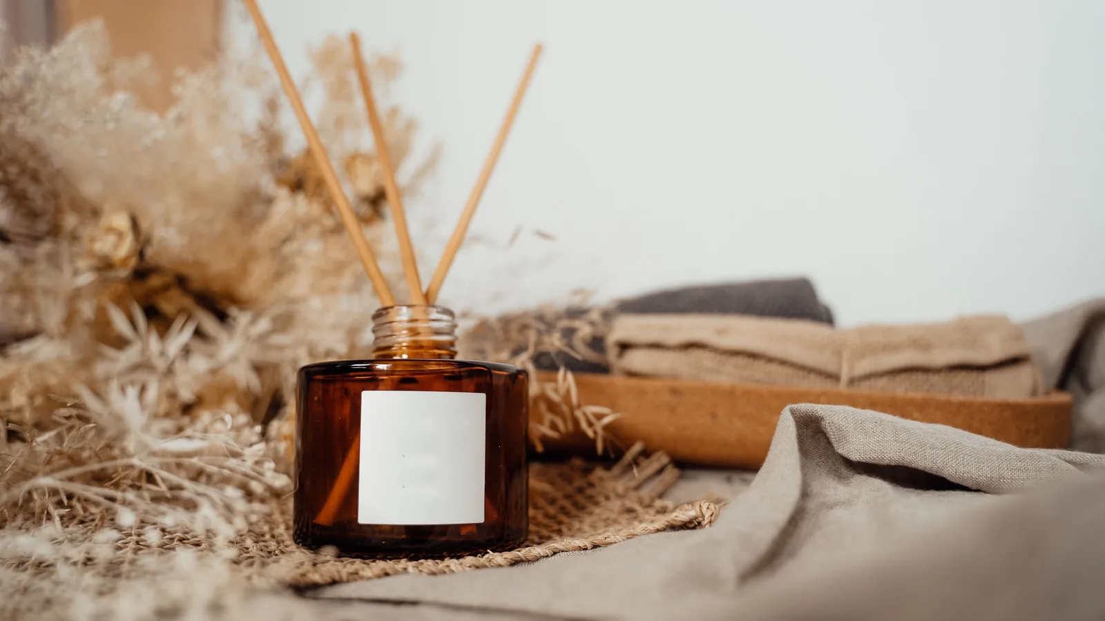 Diffusore di aromi con bastoncini, fiori secchi e asciugamani di lino in un ambiente spa dai toni caldi