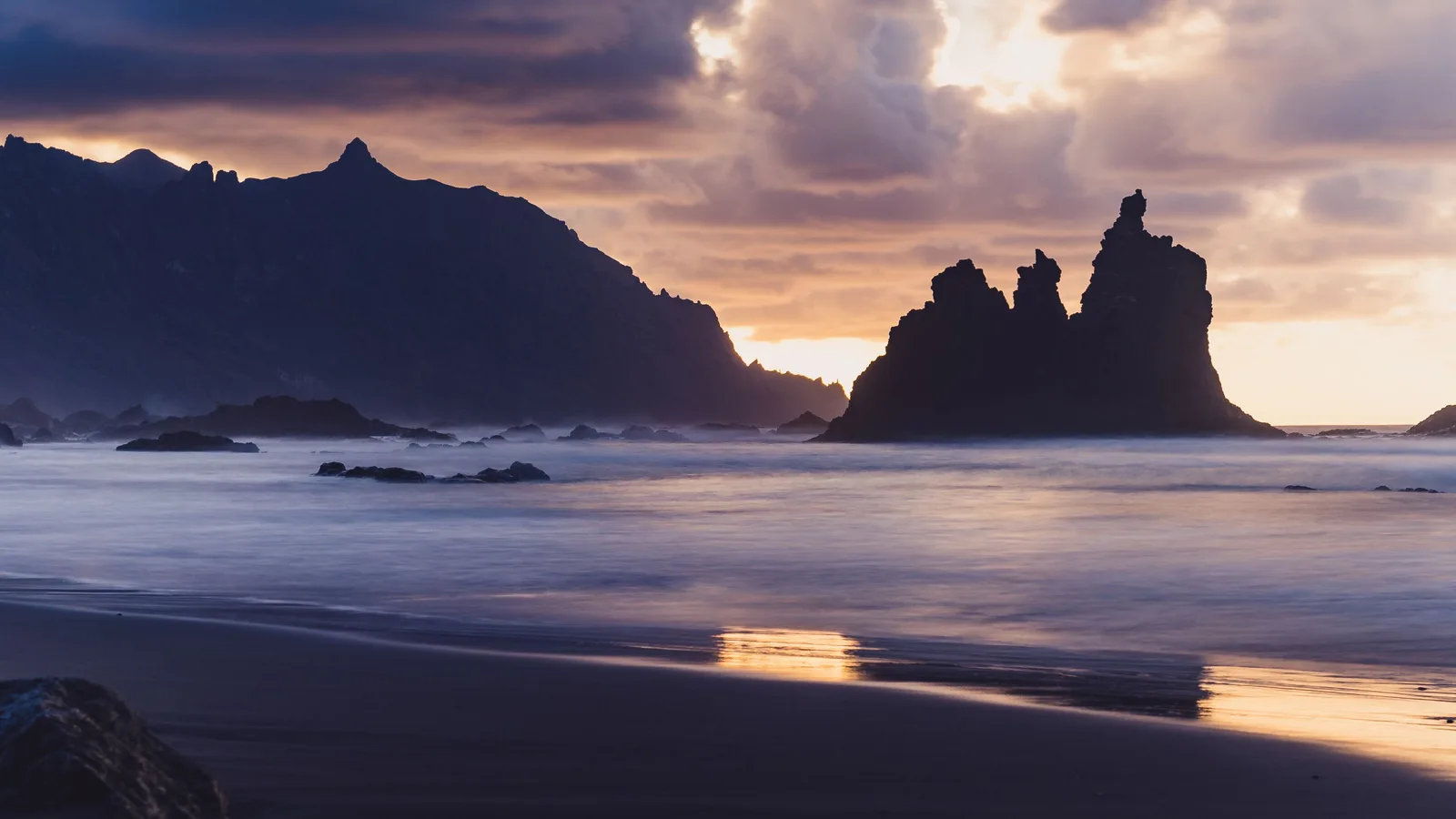 Playa de Benijo en Tenerife al atardecer: arena negra volcánica, los Roques de Anaga en silueta y las olas atlánticas